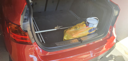 Ratchet-type cargo bar installed in car boot holding paint bucket and other diy supplies in place.