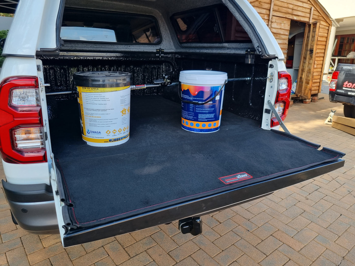 Ratchet-type cargo bar installed on back of utility vehicle with canopy holding two paint buckets in place.