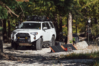 Portable power station and solar panels set up outdoors near off-road SUV.