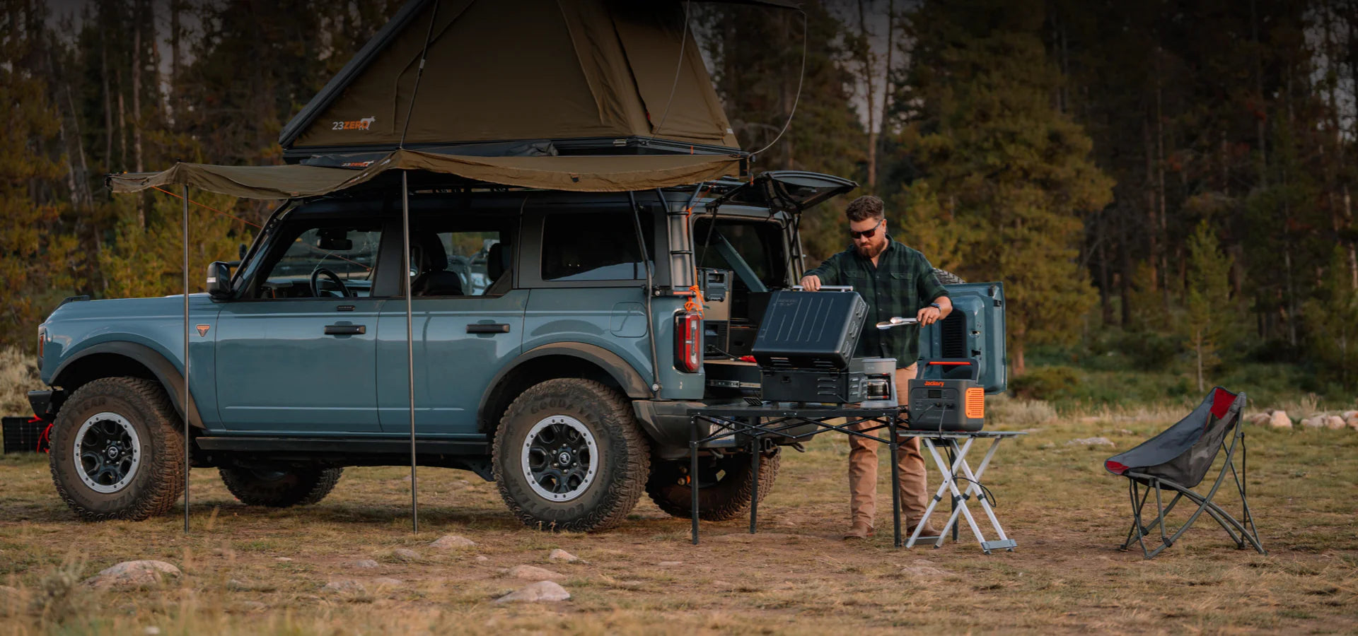 Jackery Explorer 1000 portable power station used outdoors during camping next to off-road SUV.