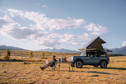 Caucasian man working on his laptop while camping.