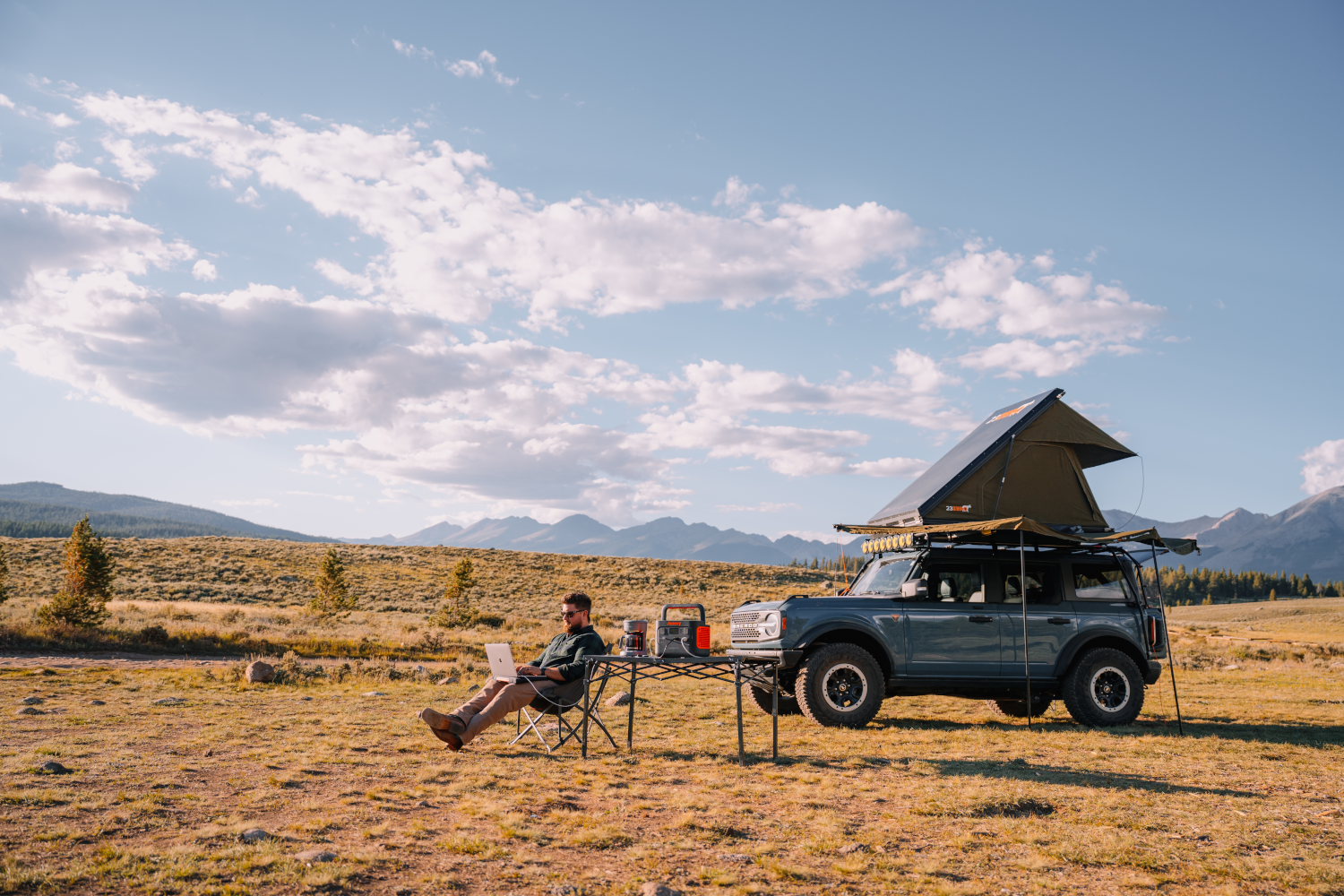 Caucasian man working on his laptop while camping.