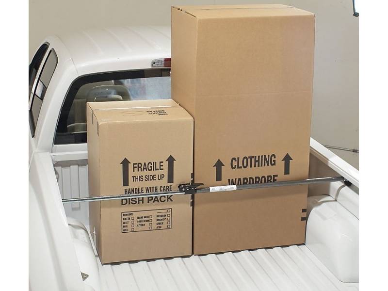 Ratchet-type cargo bar installed on back of utility vehicle holding two boxes in place.